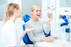Happy dental patient looking in mirror