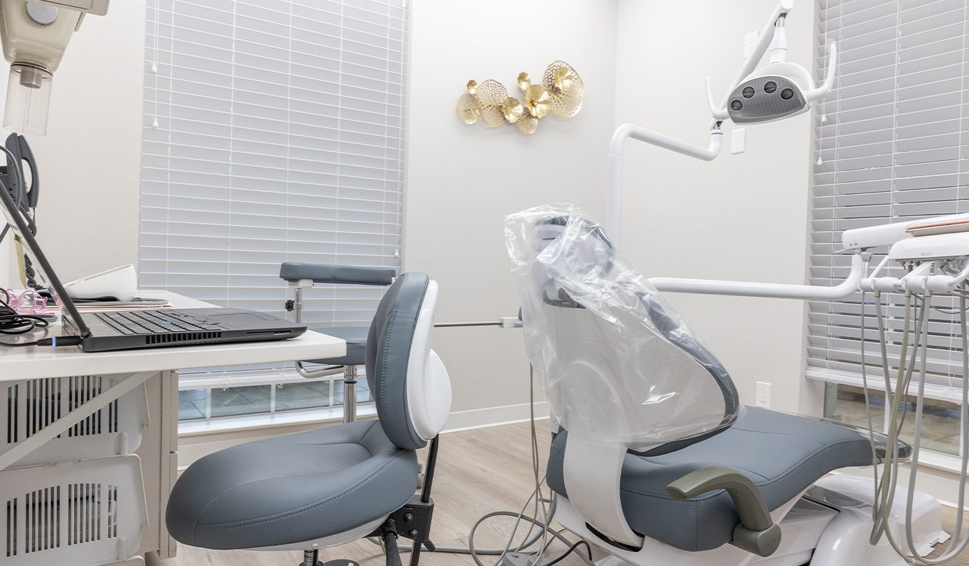 Dental exam chair next to shelf with open laptop on it