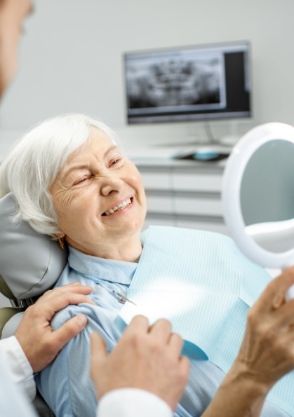 Senior dental patient seeing her new smile in mirror