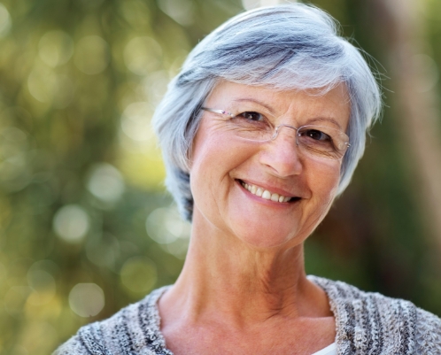 Senior woman with glasses smiling outdoors