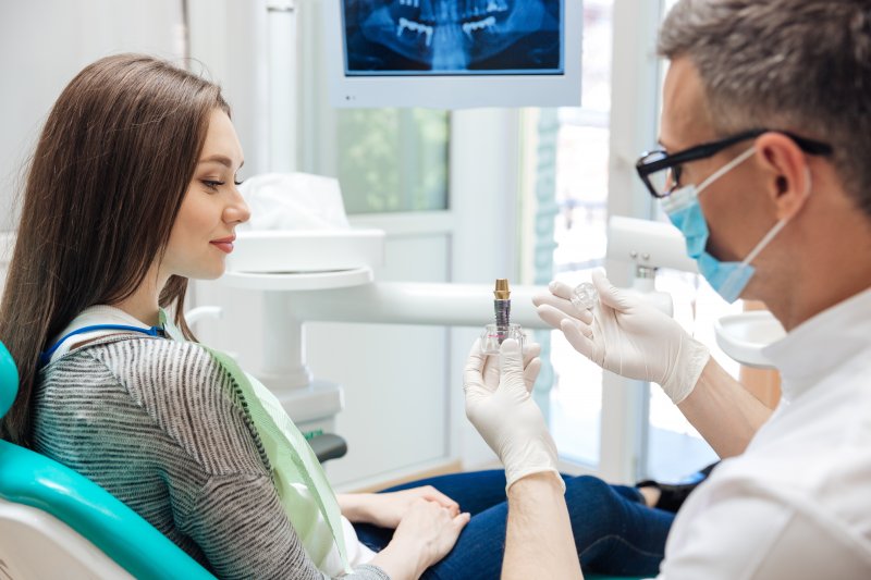 A dentist talking with his patient about how dental implants can fail